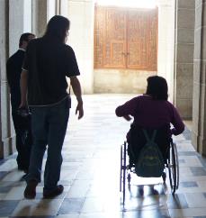 Mujer en silla de ruedas acompañada por dos personas más