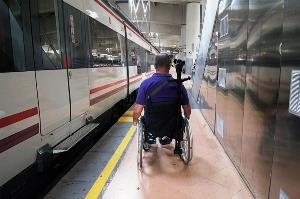 Un usuario de silla de ruedas pasa por un estrecho pasillo de un andén de Cercanías, en Atocha