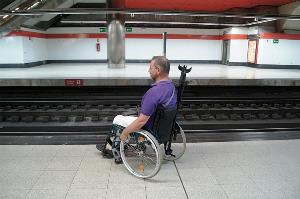 Usuario de silla de ruedas en un andén de Cercanías, en Nuevos Ministerios, con una señalización poco clara y segura, se confunde la misma con las propias vías, con evidente riesgo de caída