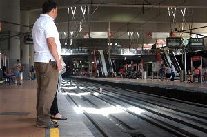 Dos pasajeros en el andén, pisando la línea amarilla que apenas advierte del peligro de cercanía a las vías y posible caída