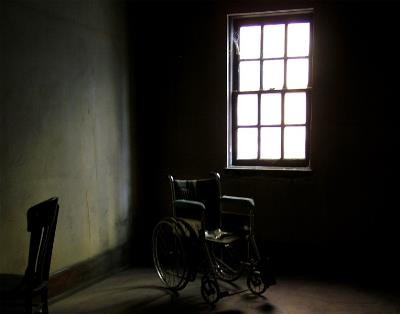Ventana, desde el interior, de un psiquiátrico y una silla de ruedas delante de ella