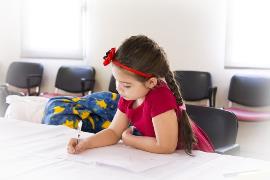 Una niña escribiendo sola en algún despacho de un colegio