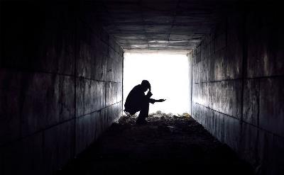 Un hombre pide limosna en la entrada de un túnel