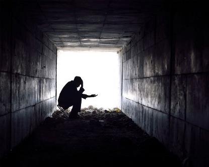 Detalle de un hombre en sombra pidiendo limosna a la entrada o salida de un túnel