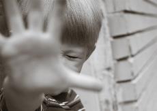 Imagen de un niño que alza la mano con gesto defensivo