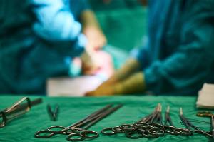 Material de cirugía y al fondo una intervención quirúrgica