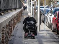 Una persona en un vehículo para movilidad reducida en una acera de ciudad