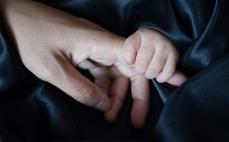 Un bebé y su madre se dan la mano