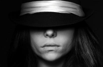 Mujer entre sombras con los ojos cubiertos por un sombrero