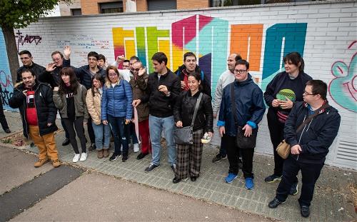 Grupo de personas con discapacidad delante de un muro en el que se ha escrito el título de la iniciativa 'Titales'