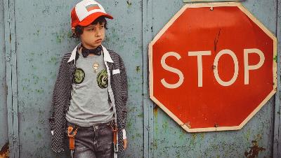 Imagen de un niño con una señal de stop al lado