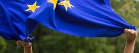 Unas manos ondean la bandera de la Unión Europea