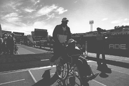 En un recinto deportivo, un hombre empuja una silla de ruedas de otra persona