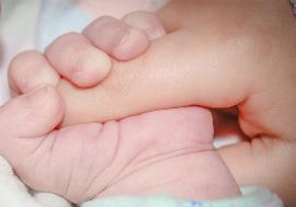 Mano de bebé agarra con fuerza el dedo de un adulto