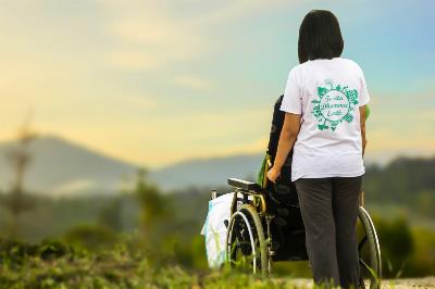 Una asistente y una mujer en silla de ruedas observan el campo.