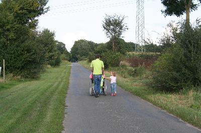 Una familia con una persona en silla de ruedas, dan un paseo por el campo.
