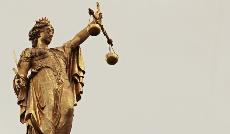 Estatua de la Justicia, con los ojos tapados agarrando una espada y una balanza.