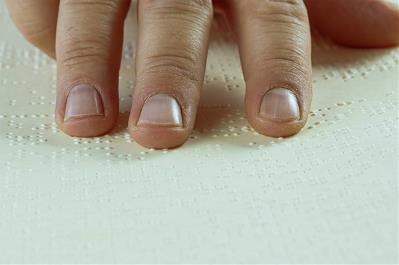 Detalle de los dedos de una mano leyendo braille