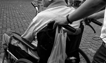 Hombre en silla de ruedas empujada por otra persona