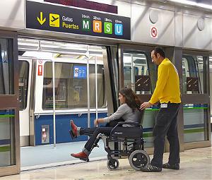Una joven en silla de ruedas intenta acceder al metro, con la ayuda de un asistente