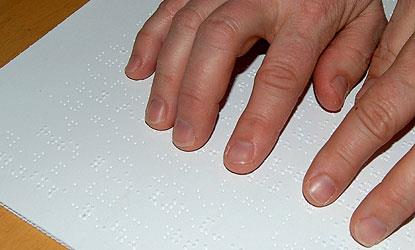 Manos de una persona con discapacidad visual leyendo un texto en braille