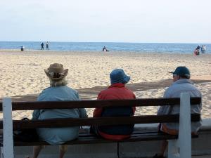 Personas mayores sentadas en un banco en la playa
