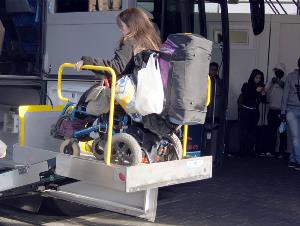 Mujer en silla de ruedas que accede a un autobús en un elevador