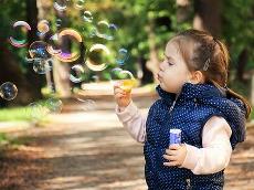 Un niño pequeño jugando con pompas de jabón en el parque