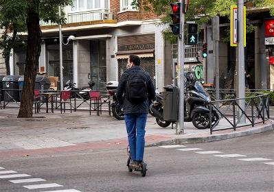 Hombre en patinete circulando sobre paso de peatones