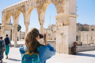 Una mujer fotografía un edificio de la antigüedad en ruinas.